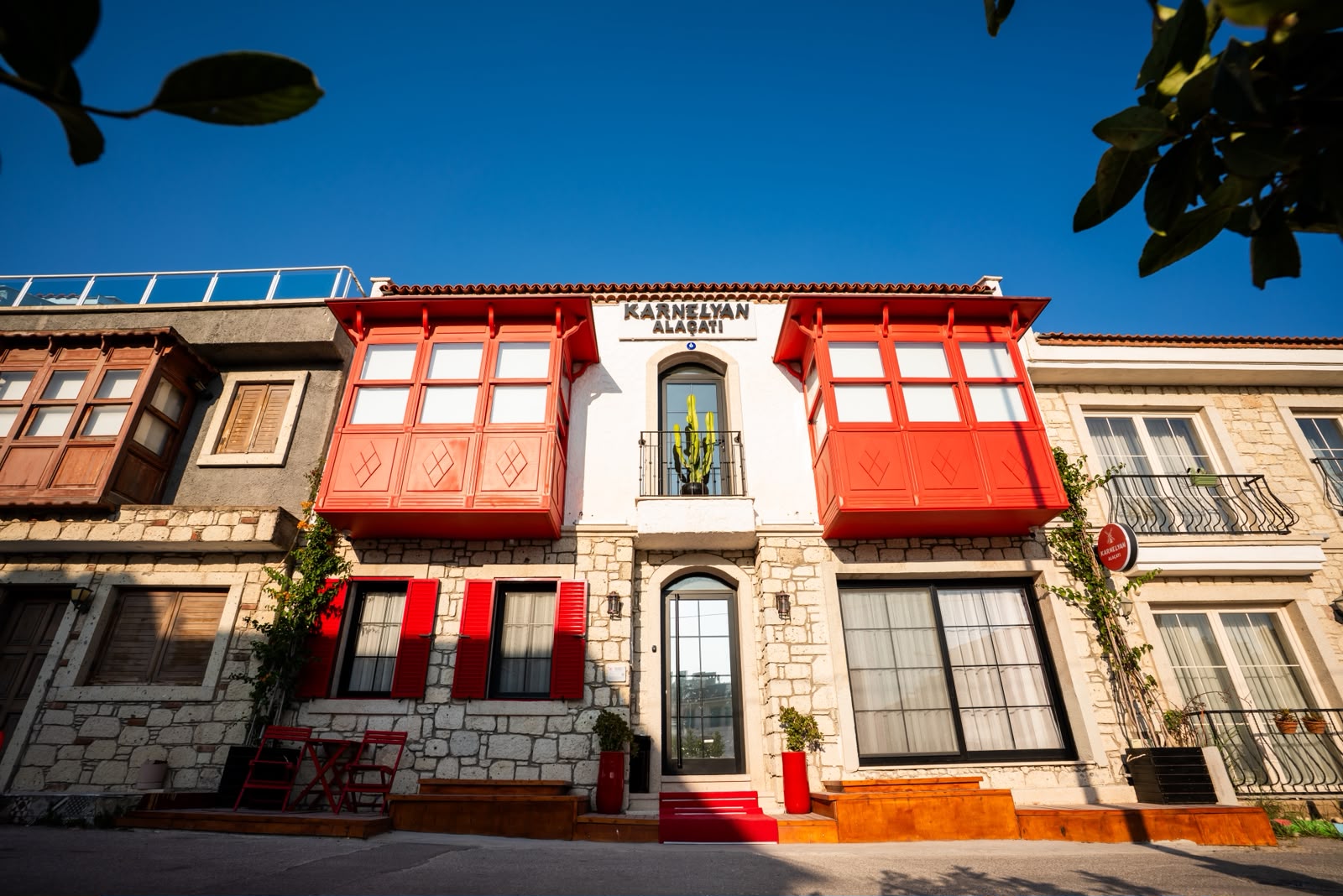 Karnelyan Alaçatı — kırmızı cumbalı taş bina